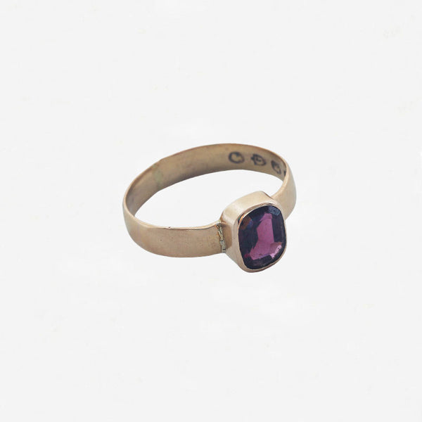 Gold ring with a garnet gemstone on a white background