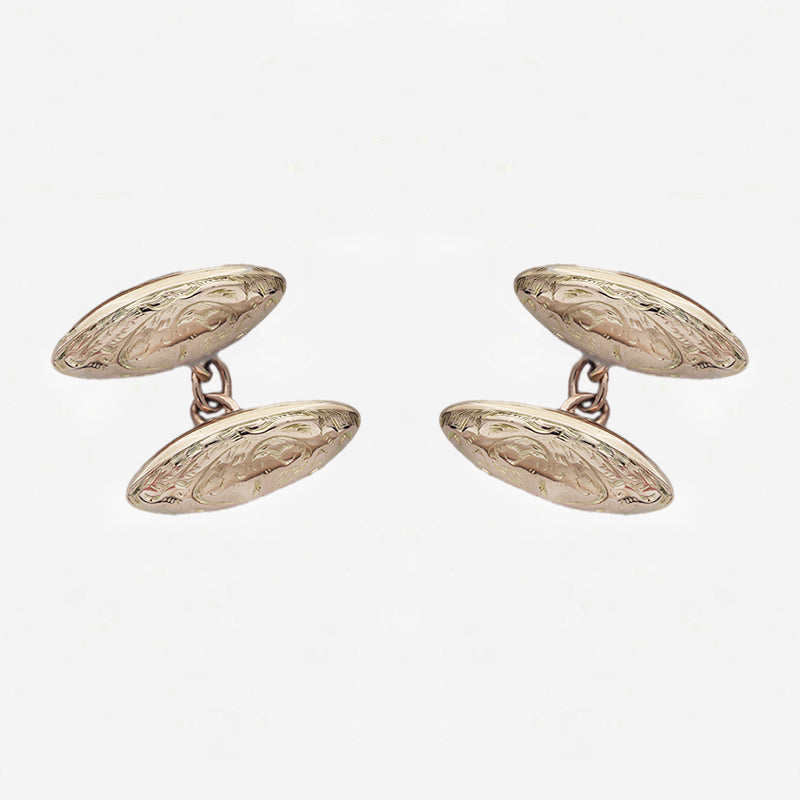 Pair of gold cufflinks on a light grey background