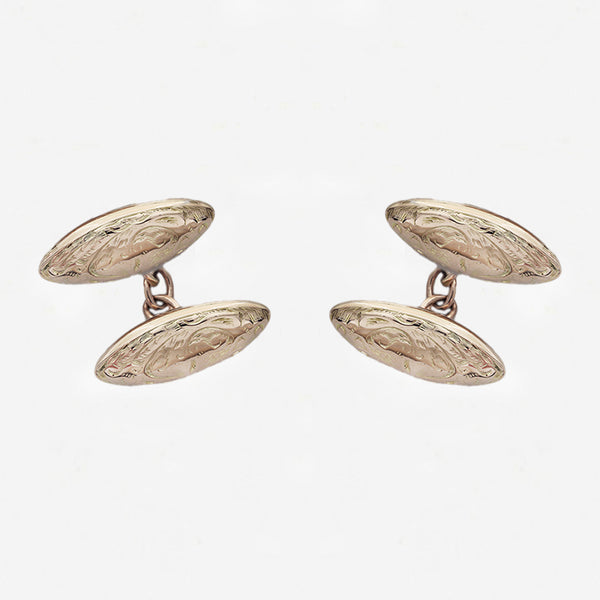 Pair of gold cufflinks on a light grey background