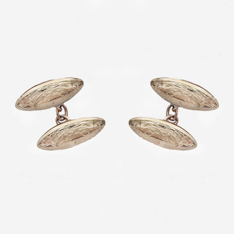 Pair of gold cufflinks on a light grey background