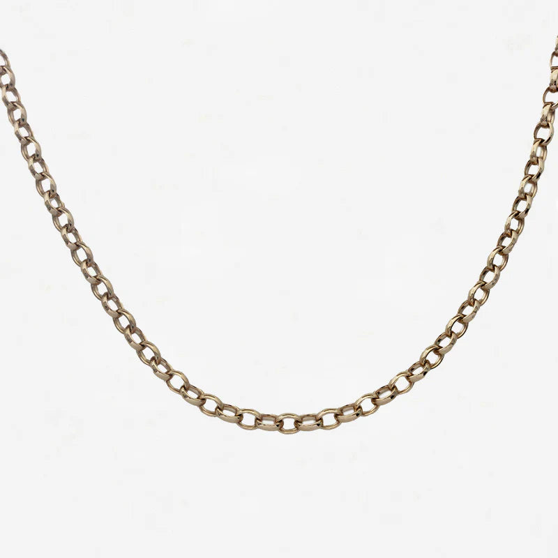 Gold chain necklace on a light grey background