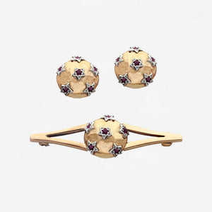 Gold jewelry set with round designs and gemstones on a white background