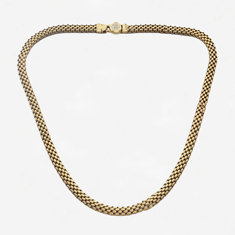 Gold chain necklace on a light grey background