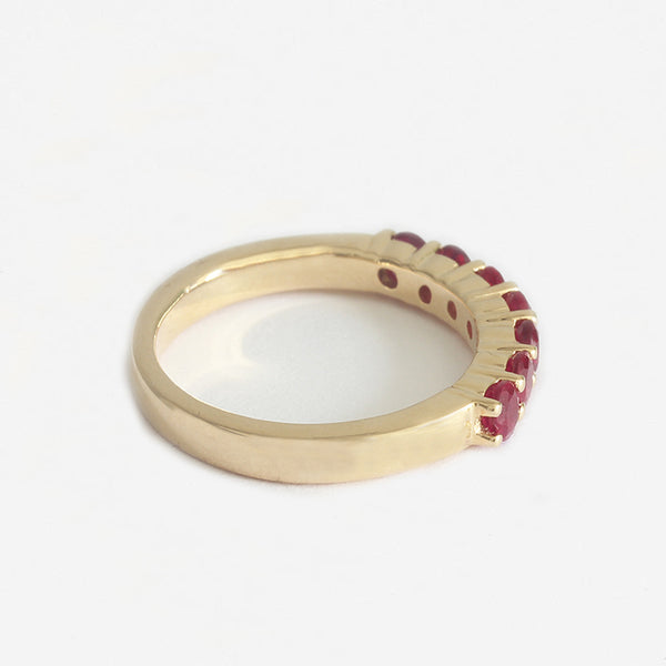 a yellow gold ruby half eternity ring with 7 round stones and claw set