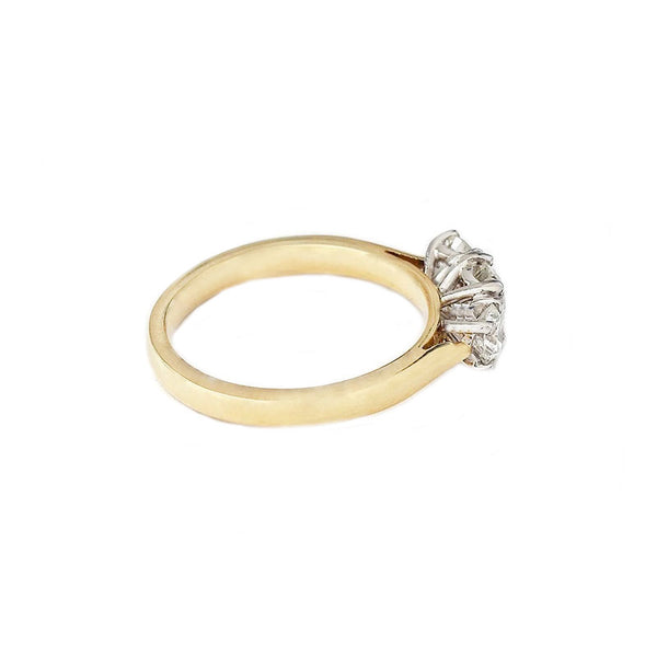 Side view of a three stone brilliant cut diamond ring in yellow gold. The diamonds are four claw set in white gold