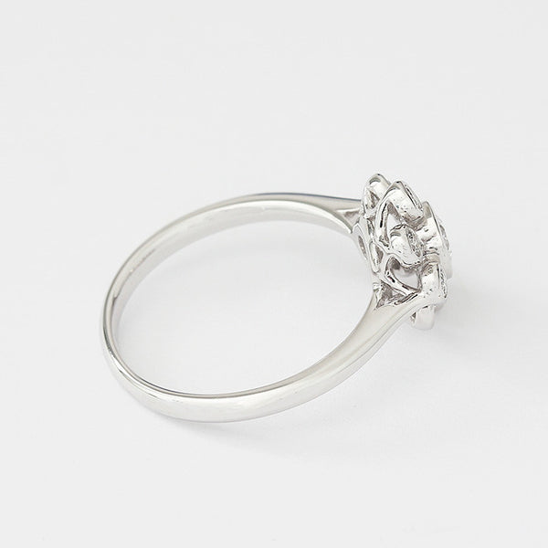 Side view of a nine stone Diamond cluster ring in 18ct white gold. There is a central round diamond with the others surrounding it in a flower design. Diamonds are rub-over set