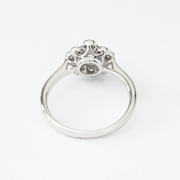 Back view of a nine stone Diamond cluster ring in 18ct white gold. There is a central round diamond with the others surrounding it in a flower design. Diamonds are rub-over set