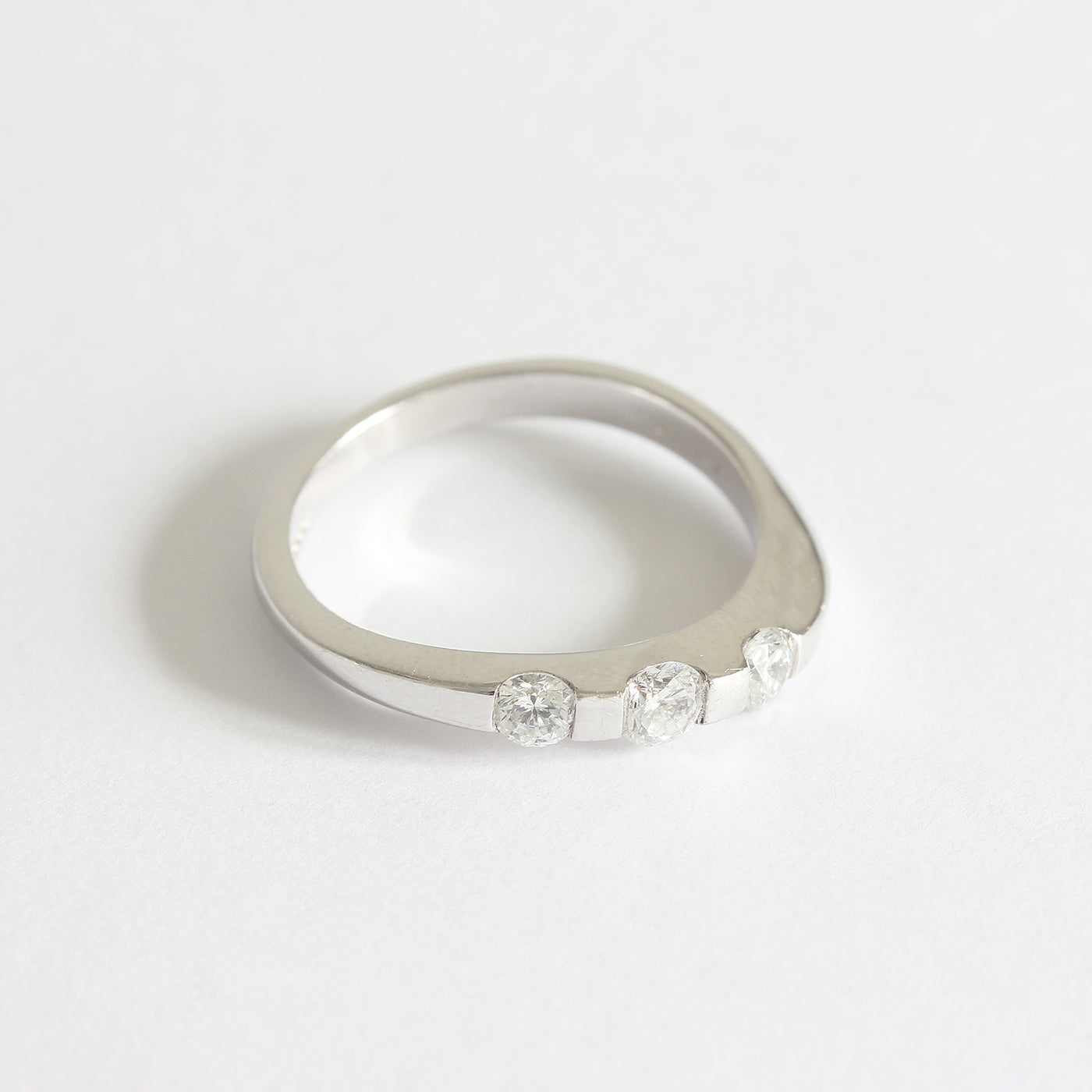 A three stone diamond ring in white gold. The diamonds are set in a tension style with curved shoulders