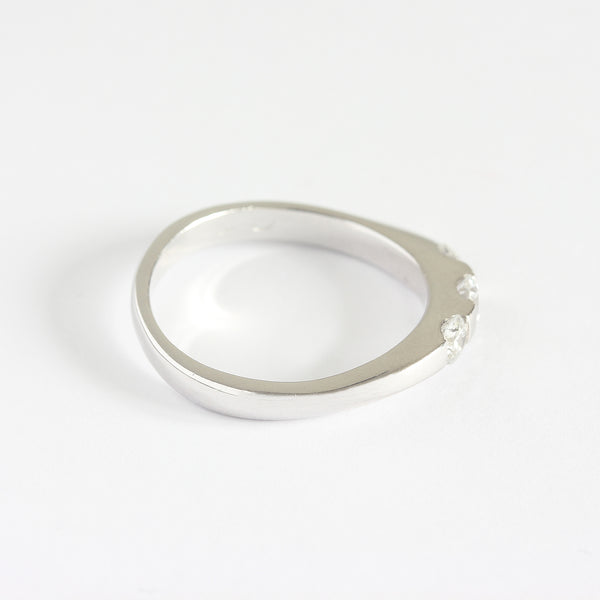 A three stone diamond ring in white gold. The diamonds are set in a tension style with curved shoulders