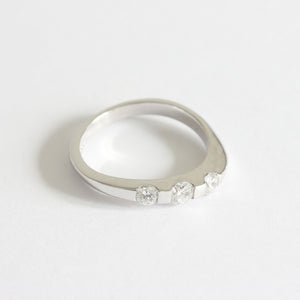 A three stone diamond ring in white gold. The diamonds are set in a tension style with curved shoulders