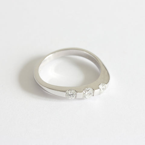 A three stone diamond ring in white gold. The diamonds are set in a tension style with curved shoulders