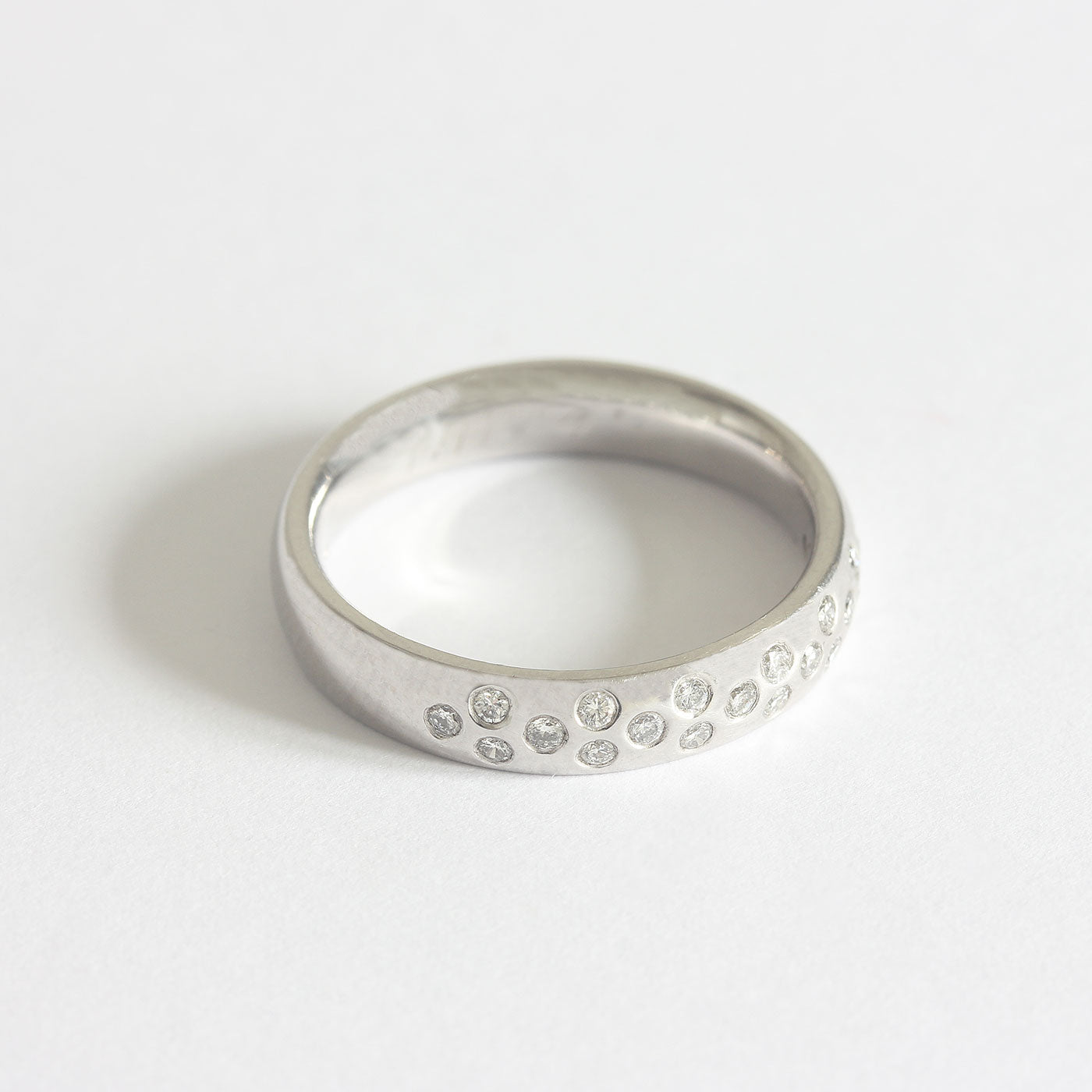 A nineteen stone diamond ring in Platinum. The circular diamonds are flush set in a 1-2-1-2 pattern around the top half of the band
