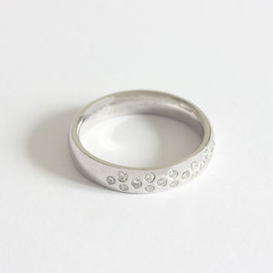 A nineteen stone diamond ring in Platinum. The circular diamonds are flush set in a 1-2-1-2 pattern around the top half of the band