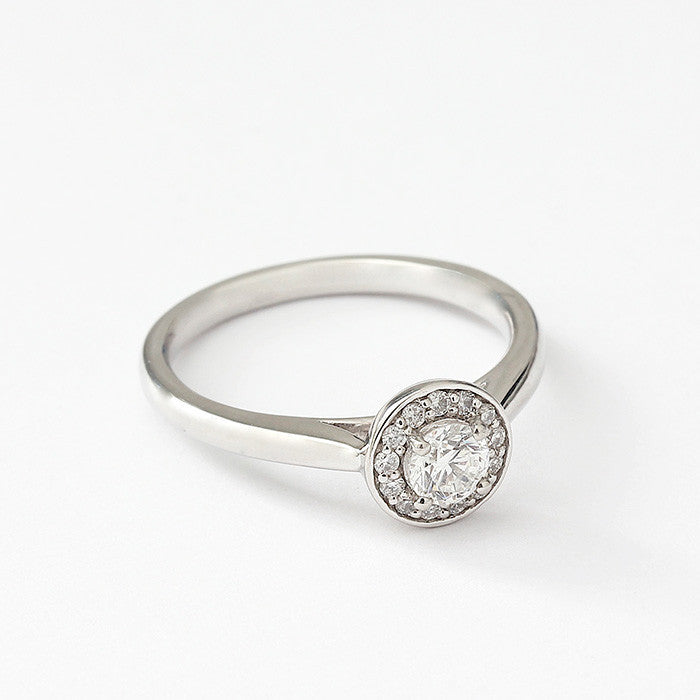 A Diamond cluster ring in platinum. There is a single round diamond to centre in a raised four claw setting surrounded by smaller diamonds