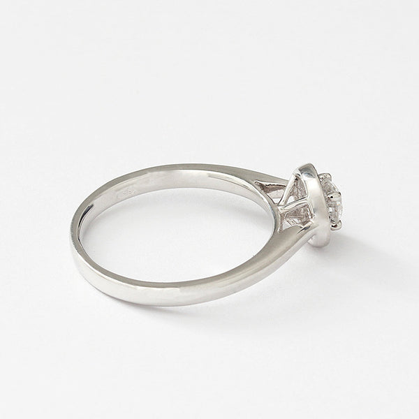 Side view of a Diamond cluster ring in platinum. There is a single round diamond to centre in a raised four claw setting surrounded by smaller diamonds