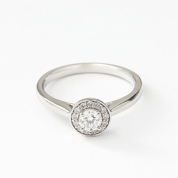 Front view of a Diamond cluster ring in platinum. There is a single round diamond to centre in a raised four claw setting surrounded by smaller diamonds