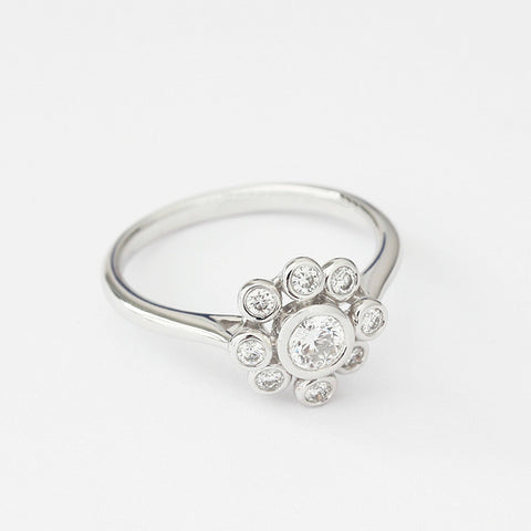 a modern diamond ring in a flower cluster design in 18ct white gold with rubover setting