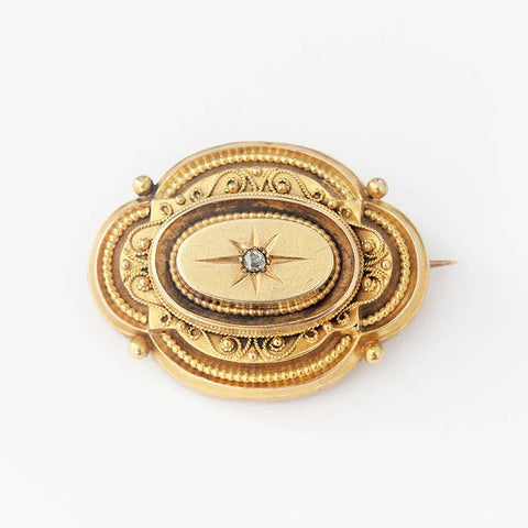 a beautiful yellow gold victorian brooch with a small central diamond and beaded design