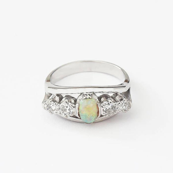 a preowned white gold central opal and diamond set band with claw setting