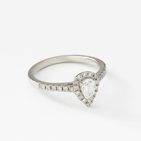 a platinum diamond cluster ring in a claw setting pear shaped centre stone