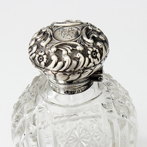 a perfume bottle with silver top and glass base dated 1902 with floral design and engraving