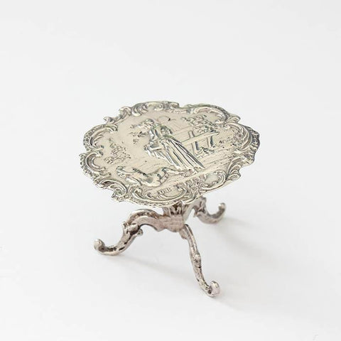 a georgian silver miniature dolls house table with decorative garden scene and 3 legs underneath dated circa 1820